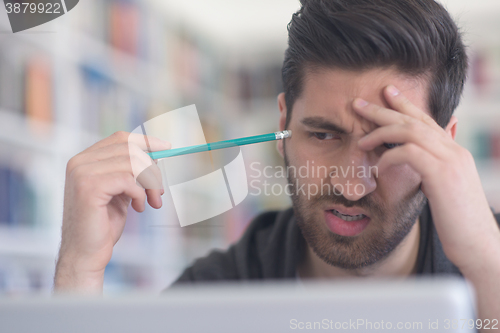 Image of student in school library using laptop for research