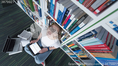 Image of female student study in library, using tablet and searching for 