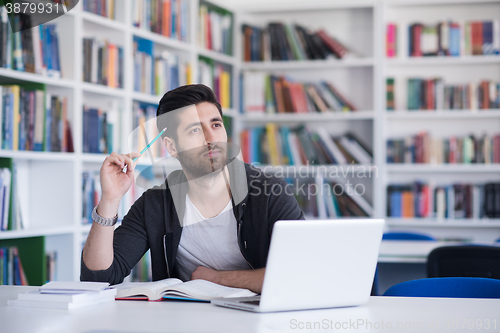 Image of student in school library using laptop for research