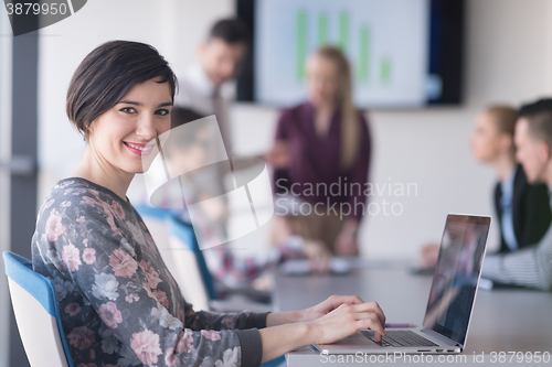 Image of young business woman at office working on laptop with team on me