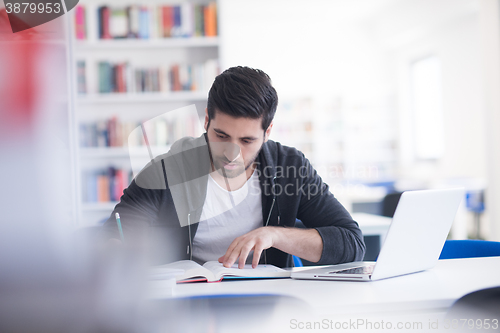 Image of student in school library using laptop for research