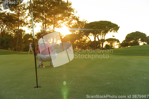 Image of golf player aiming perfect  shot on beautiful sunset