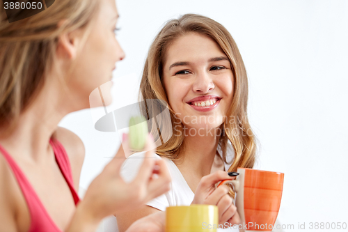 Image of happy young women drinking tea with sweets at home