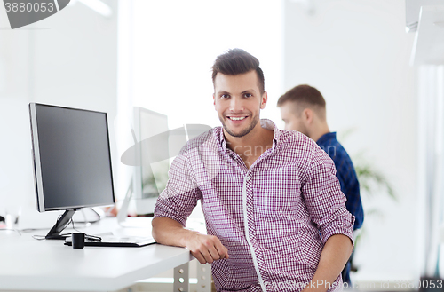 Image of happy creative man with computer at office