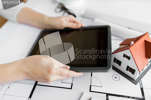 Image of close up of hand with blueprint and tablet pc