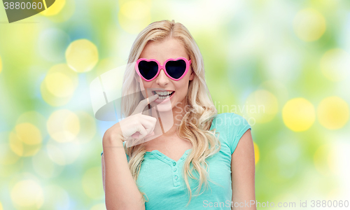 Image of happy young woman in heart shape sunglasses