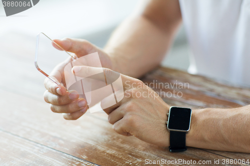 Image of close up of hands with smart phone and watch