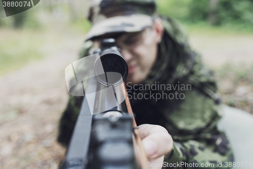 Image of close up of soldier or hunter with gun in forest