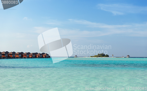 Image of bungalow huts in sea water on exotic resort beach