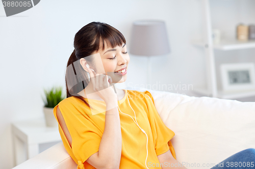 Image of happy asian woman with earphones listening music