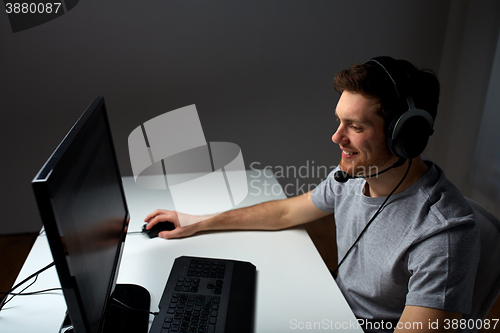 Image of man in headset playing computer video game at home