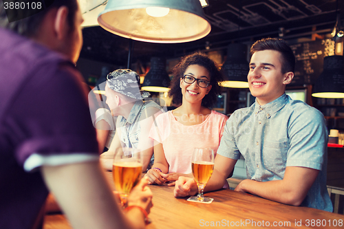 Image of happy friends drinking beer and talking at bar