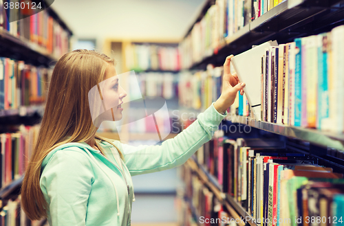 Image of happy student girl or woman with book in library
