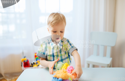 Image of happy little baby boy with ball clay at home