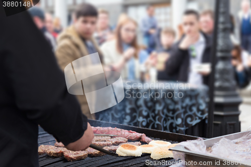 Image of Beef burgers being grilled on food stall grill.