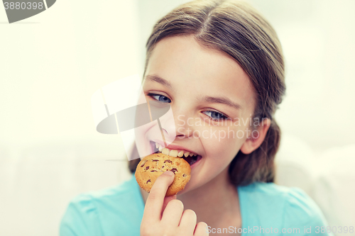 Image of smiling little girl eating cookie or biscuit