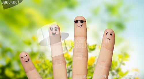 Image of close up of fingers with smiley faces over nature