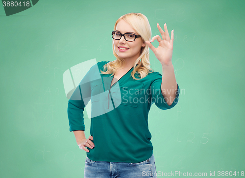 Image of smiling young woman with eyeglasses showing ok