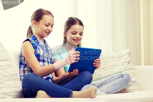 Image of happy girls with tablet pc sitting on sofa at home