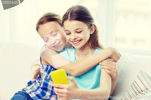 Image of happy girls with smartphone taking selfie at home