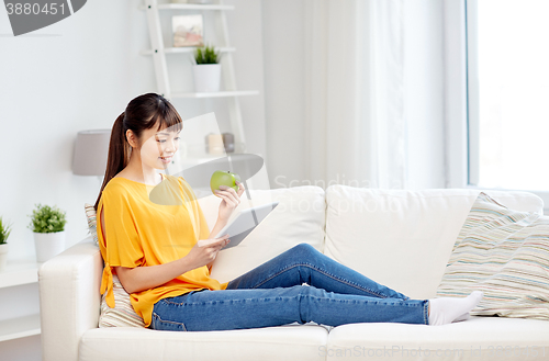 Image of happy asian woman with tablet pc and apple at home