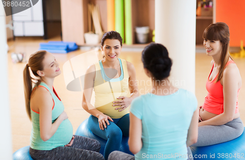 Image of happy pregnant women sitting on balls in gym