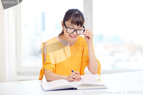 Image of happy asian young woman student learning at home