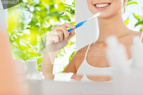 Image of woman with toothbrush cleaning teeth at bathroom