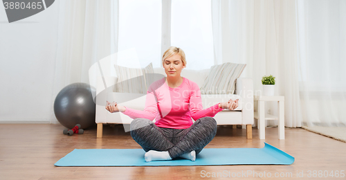 Image of happy woman stretching leg on mat at home