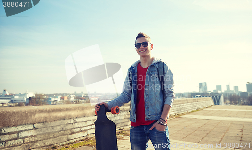 Image of smiling teenager with longboard on street