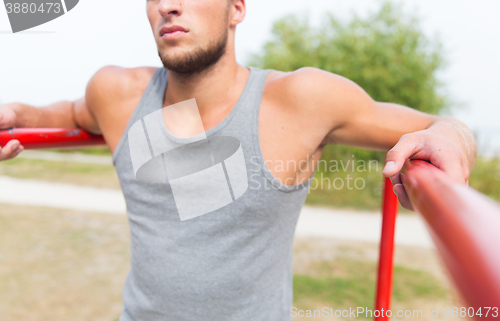 Image of close up of man exercising on parallel bars