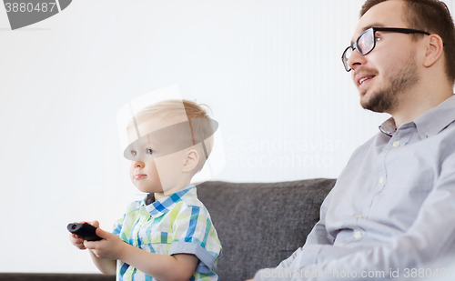 Image of father and son with remote watching tv at home