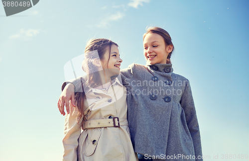 Image of happy little girls hugging and talking outdoors