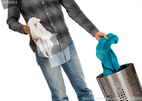 Image of Young man putting a dirty towel in a laundry basket