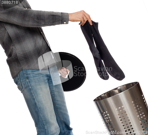 Image of Young man putting dirty socks in a laundry basket