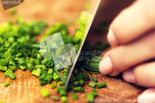 Image of close up of woman chopping green onion with knife