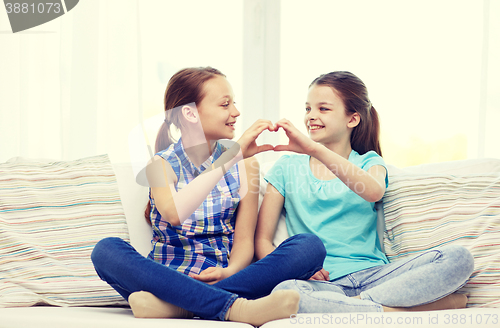 Image of happy little girls showing heart shape hand sign