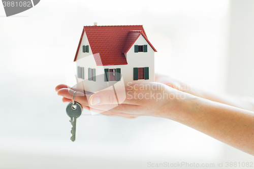 Image of close up of hands holding house model and keys