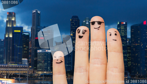 Image of close up of fingers with smiley faces over city