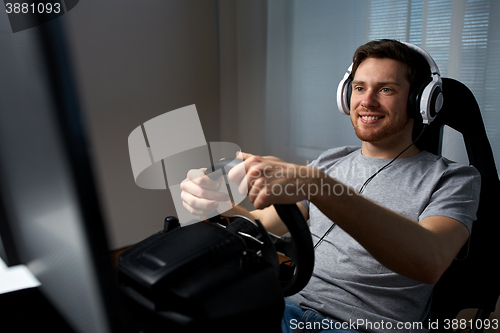 Image of man playing car racing video game at home