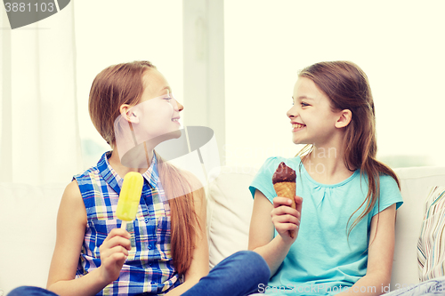 Image of happy little girls eating ice-cream at home