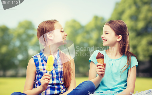 Image of happy little girls eating ice-cream in summer park