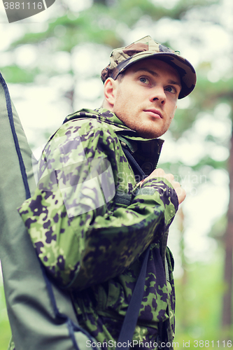 Image of young soldier or hunter with gun in forest