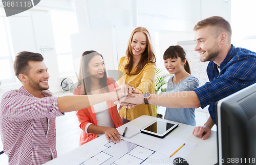 Image of creative team holding hands together  at office