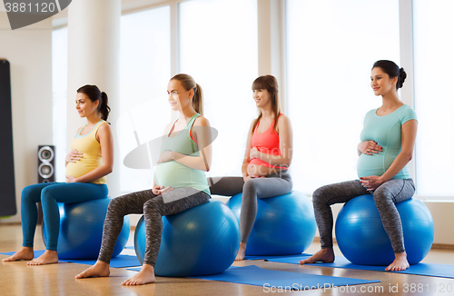 Image of happy pregnant women exercising on fitball in gym