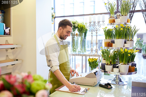 Image of florist man with clipboard at flower shop counter