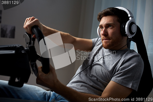 Image of man playing car racing video game at home