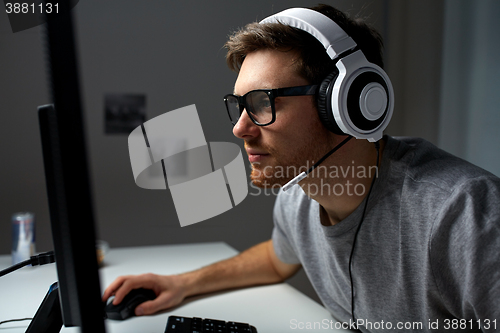 Image of man in headset playing computer video game at home