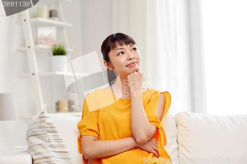 Image of happy asian young dreaming woman at home