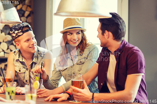 Image of happy friends drinking beer and cocktails at bar